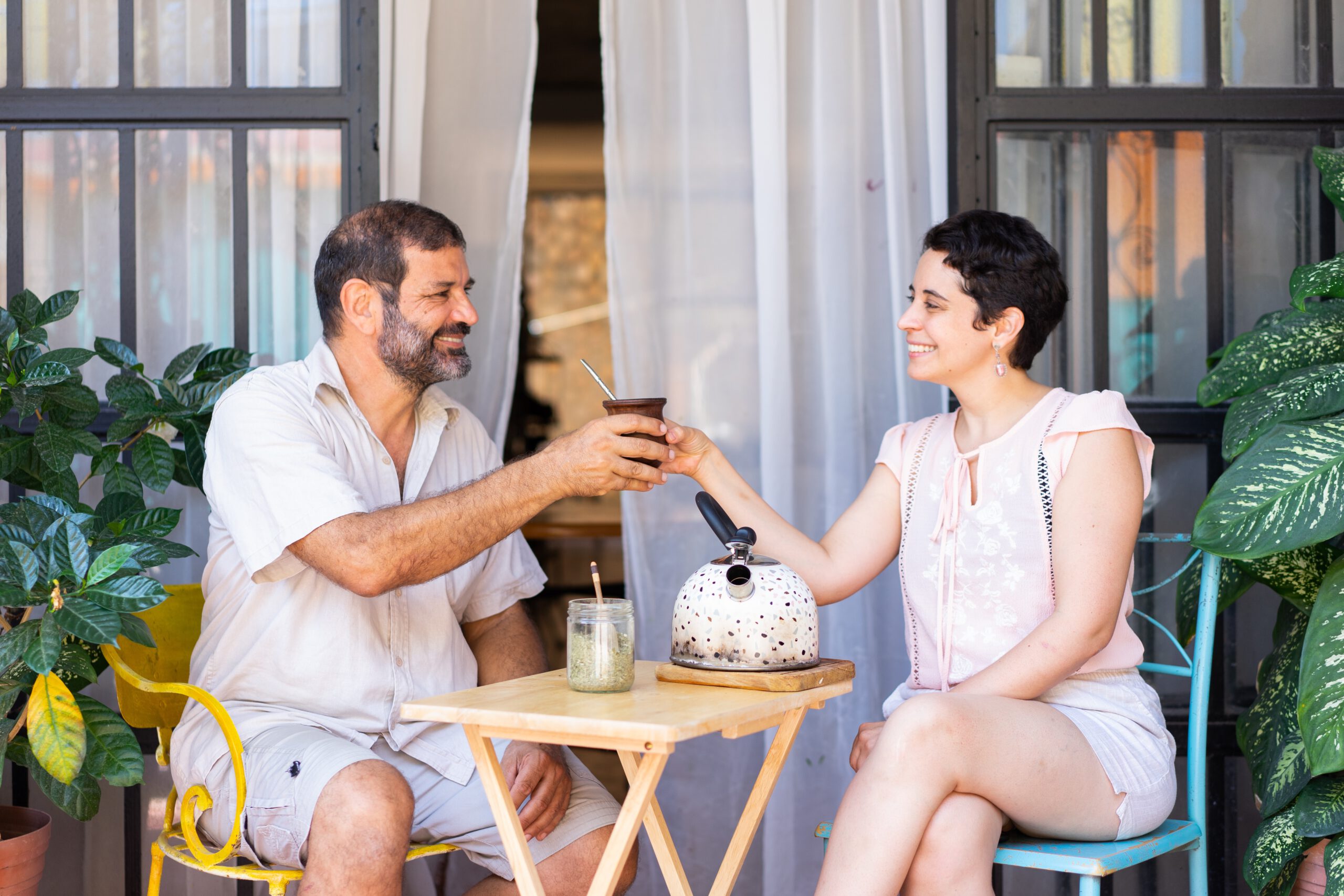 Kobieta i mężczyzna siedzący przy małym stoliku na zewnątrz i pijący yerba matę